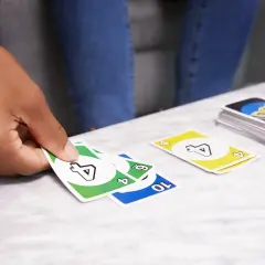 Ręka trzyma karty gry DOS. Na stole leżą karty z numerami 4, 6 i 10.