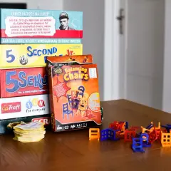 Stos pudełek z popularnymi grami dla dzieci: "5 Sekund", "Balancing Chairs", "Scrabble" i inne. Idealne na rodzinne wieczory.