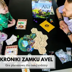 Rodzina gra w "Kroniki zamku Avel". Plansza i elementy gry rozłożone na czarnym stole, dzieci i dorosły skupieni na rozgrywce.
