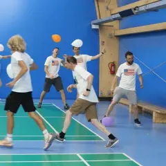 Mężczyźni w koszulkach z amerykańską flagą bawią się balonami na sali gimnastycznej. To świetna integracja dla dorosłych!