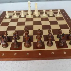 Ułożenie pionków w szachach. Drewniana szachownica z ciemnymi i jasnymi figurami, gotowa do gry.