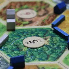 Drewniane domki i drogi na planszy do gry strategicznej. Gracze budują osady, by zdobyć surowce i rozwijać swoje imperium.