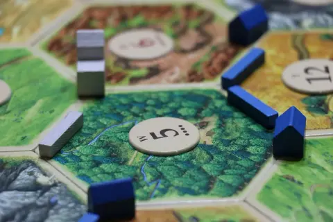Catan gra planszowa zasady: drewniane osady i drogi na heksagonalnej planszy.
