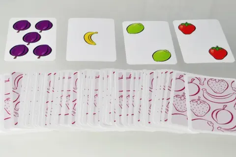 Karty do gry halli galli z owocami: śliwki, banan, limonki, truskawki. Stos kart z owocowym wzorem.