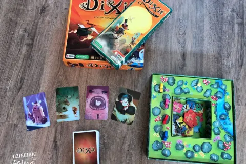Kret gra w Dixit, rozłożone karty i plansza z numerami.