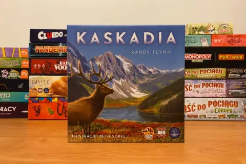 Gra planszowa Kaskadia z jeleniem na okładce, otoczona innymi grami jak Cluedo, Pandemic, Monopoly.