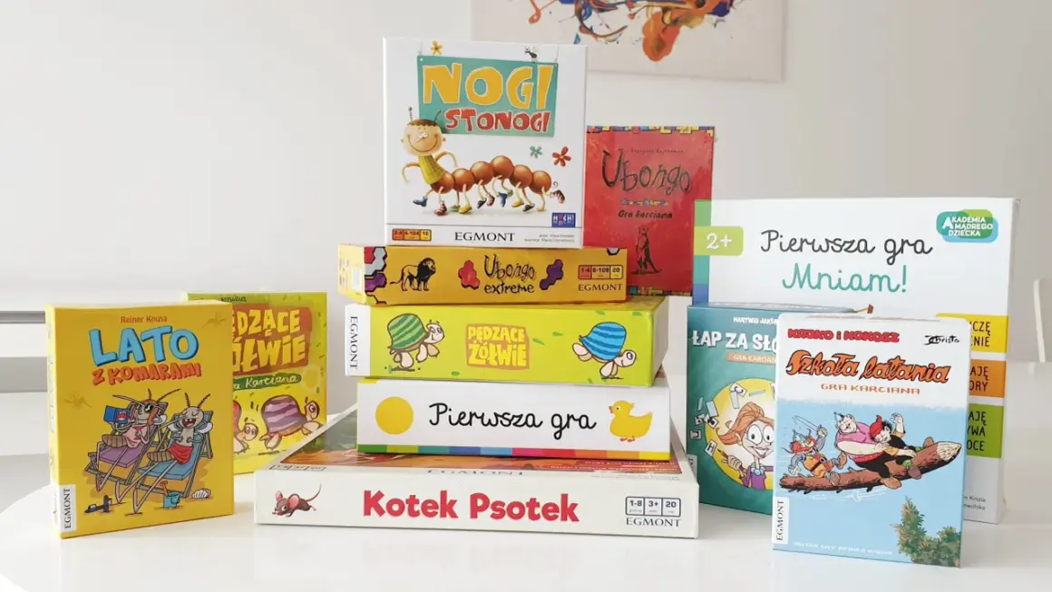 Stos kolorowych pudełek z grami planszowymi, idealnych na szybkie gry planszowe. Widać m.in. "Nogi Stonogi", "Ubongo" i "LATO z Komarami".