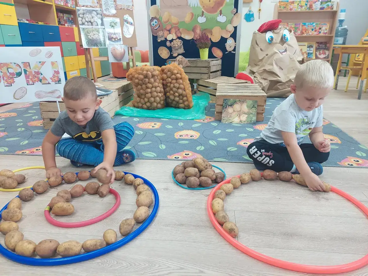 Dwóch chłopców bawi się ziemniakami, układając je w kółka. To świetna gra w ziemniaka!